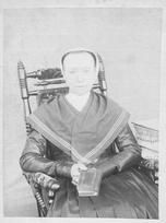 SA0044 - She is seated in an upholstered chair holding a book. Identified on reverse., Winterthur Shaker Photograph and Post Card Collection 1851 to 1921c